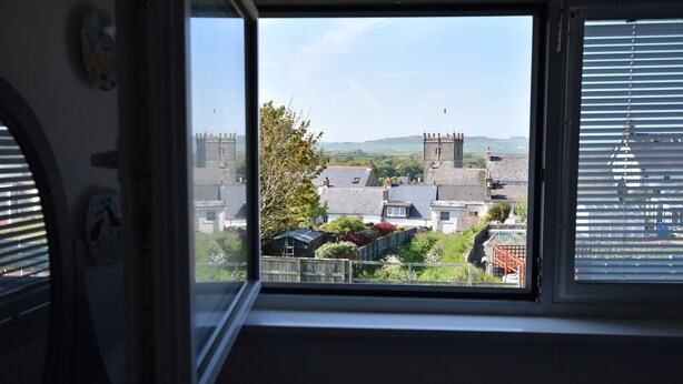 Une vue depuis une fenêtre, avec un ciel dégagé, une clôture en bois et des maisons en arrière-plan.
