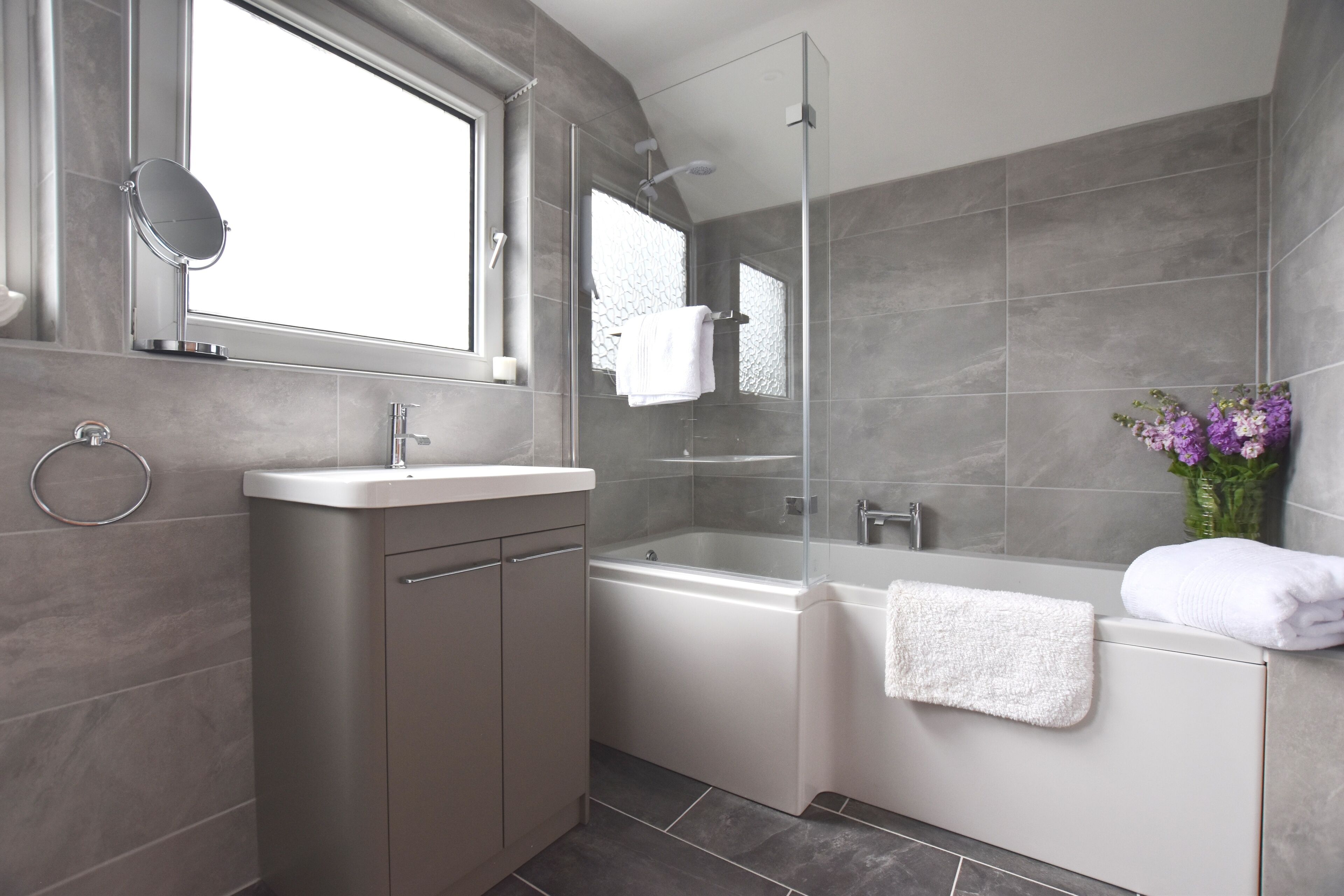 Un bagno moderno con doccia a vetro, una vasca da bagno freestanding e un mobile lavabo con specchio.