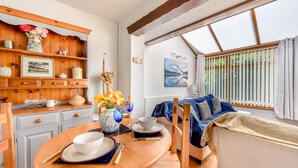 A cozy dining area with a wooden table, chairs, and a blue sofa. - Covert Farm Cwtch (Kilgetty)