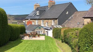 Une maison avec un toit en pente, des murs en pierre et une pelouse bien entretenue.