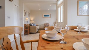 Un coin repas avec une table en bois dressée pour le repas, des chaises et un canapé en arrière-plan.