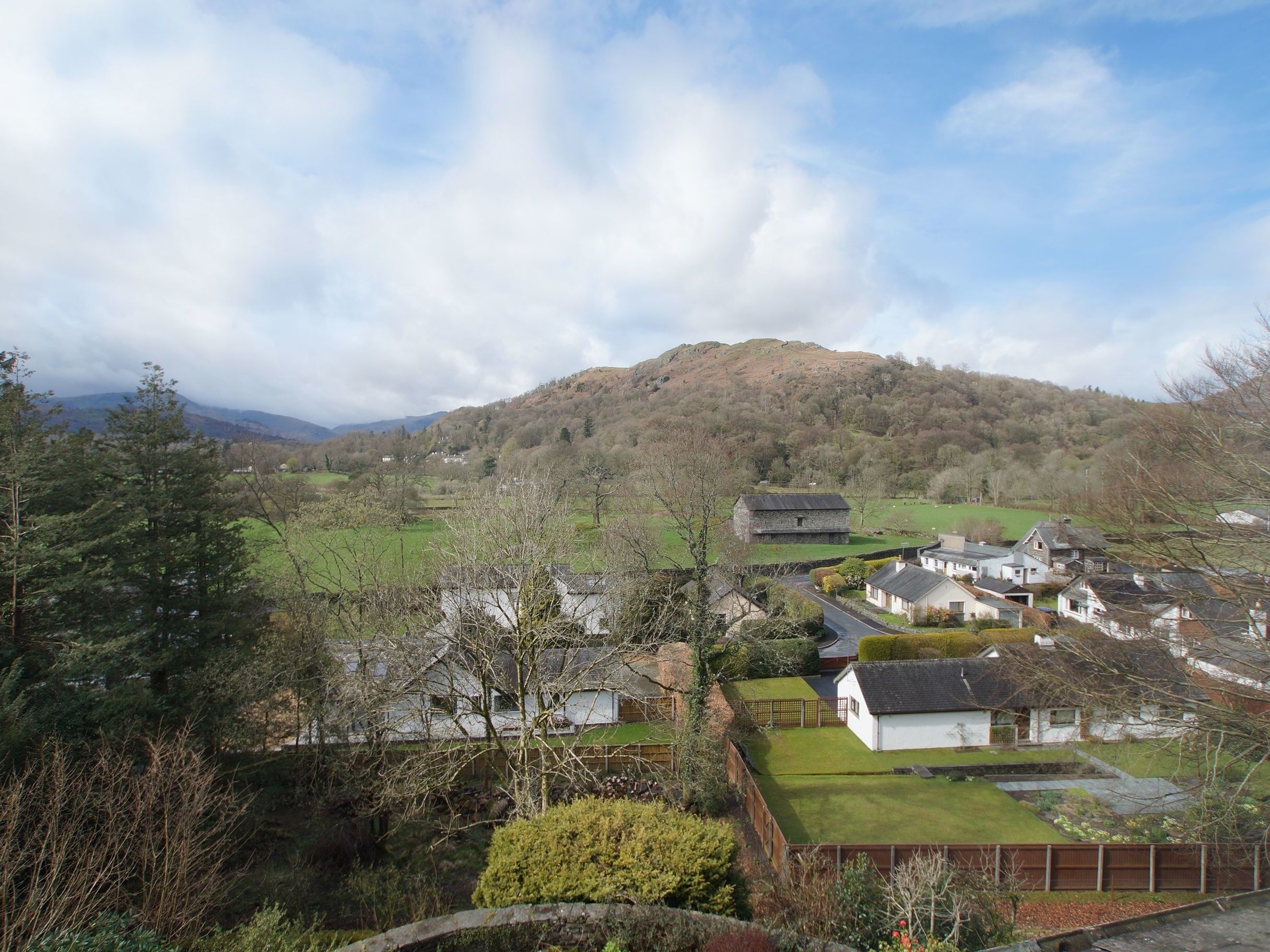 A rural village with stone houses, a hill in the background, and a clear sky.