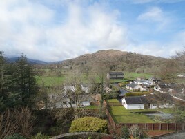 A rural village with stone houses, a hill in the background, and a clear sky.