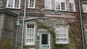 Un edificio de piedra con varias ventanas, una puerta y conductos eléctricos visibles.