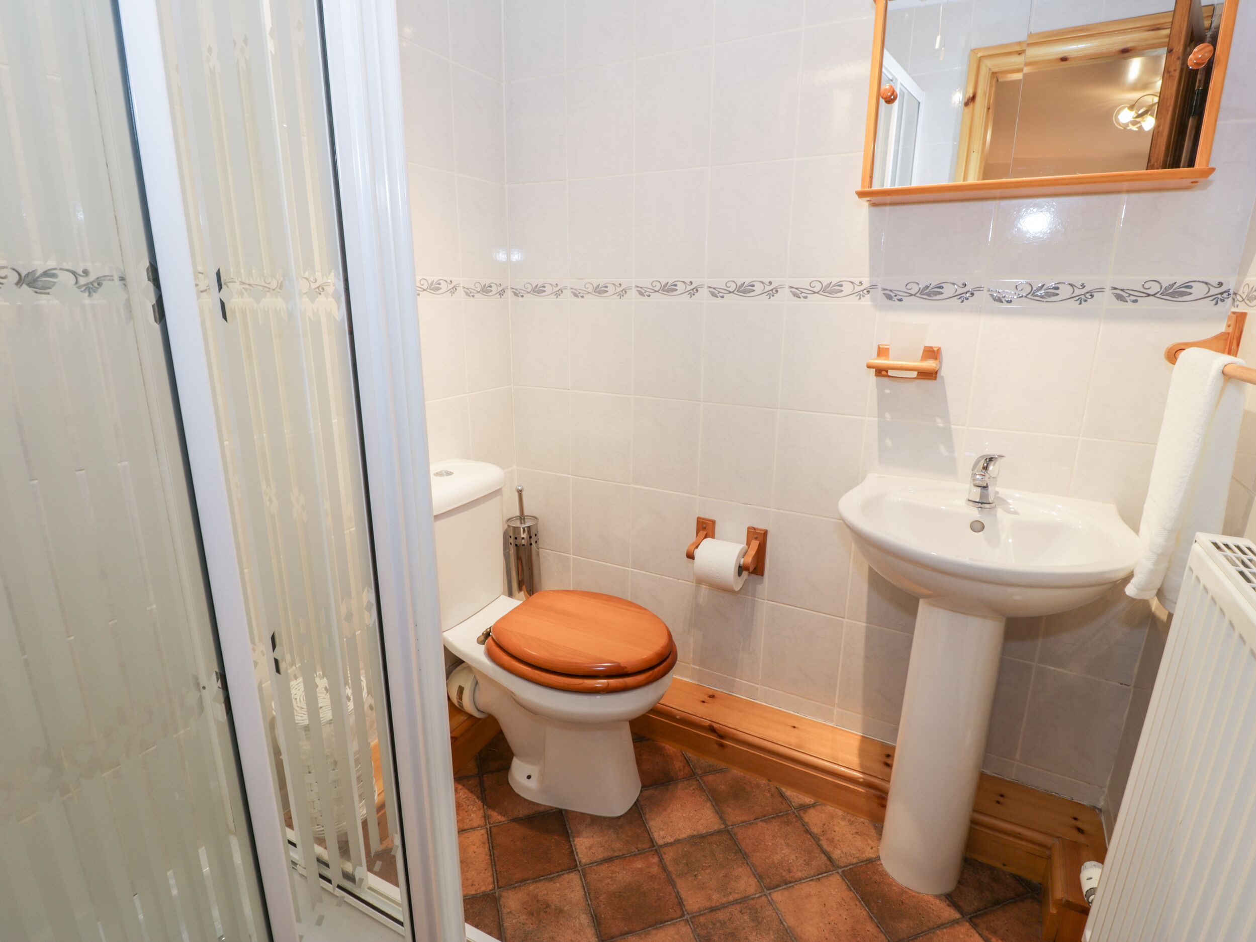 A bathroom with a toilet, sink, and mirror.