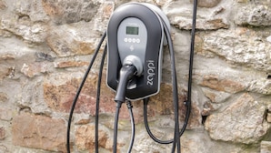 Une borne de recharge pour véhicules électriques fixée à un mur en pierre.