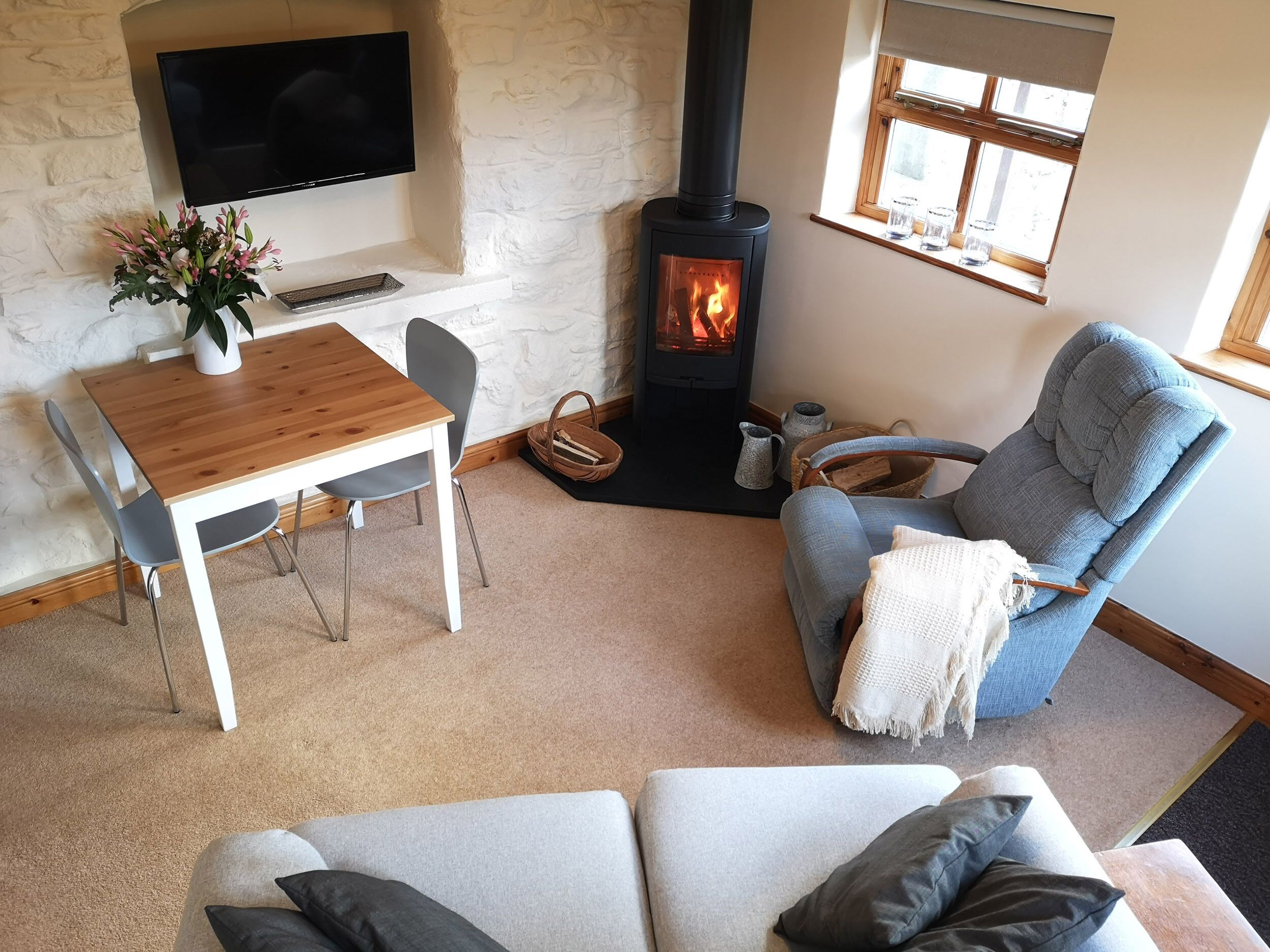 A cozy living room with a fireplace, a TV mounted on a stone wall, and a comfortable seating area.