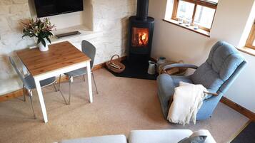 A cozy living room with a fireplace, a TV mounted on a stone wall, and a comfortable seating area.