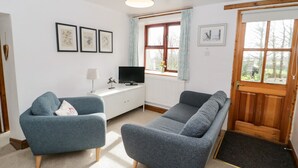 Un salon moderne avec un canapé, un fauteuil, un téléviseur et des tableaux encadrés accrochés au mur.