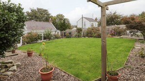 A well-maintained backyard with a wooden pergola, a lawn, and potted plants. - Victoria Cottage (Berwick-upon-Tweed)