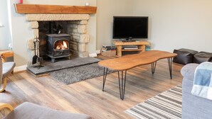 A living room with a stone fireplace, a television, and a sofa. - Victoria Cottage (Berwick-upon-Tweed)