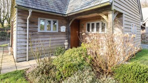 Ein Holzhaus mit geneigtem Dach, einer Veranda und einem kleinen Garten mit verschiedenen Pflanzen.