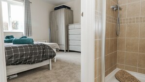 Ein Schlafzimmer mit Bett, Kleiderschrank und Duschbereich.