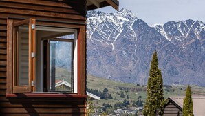 Uma cabana de madeira com uma janela grande que oferece vista para montanhas cobertas de neve.
