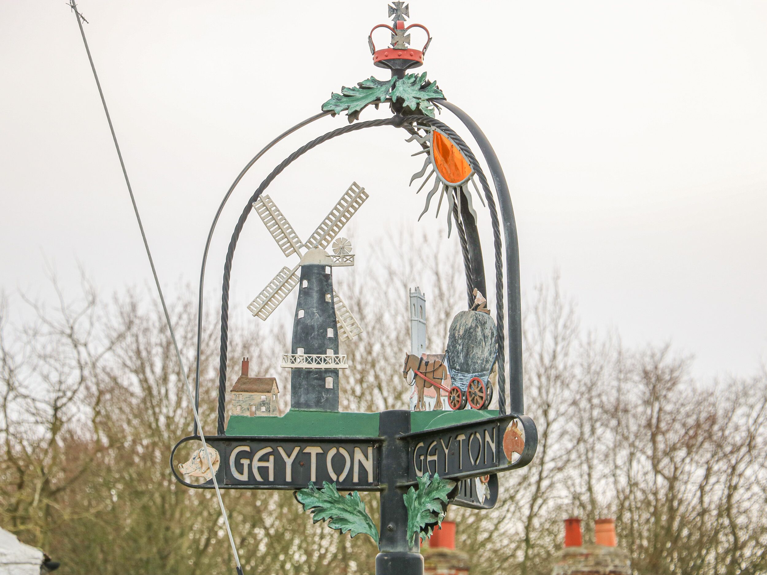 A windmill sign with a house and a horse, and the name 'Gayton' on it.