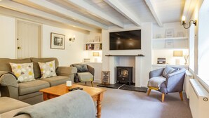 A cozy living room with a fireplace, a television, and a bookshelf. - 3 Rose Cottages (St. Agnes)