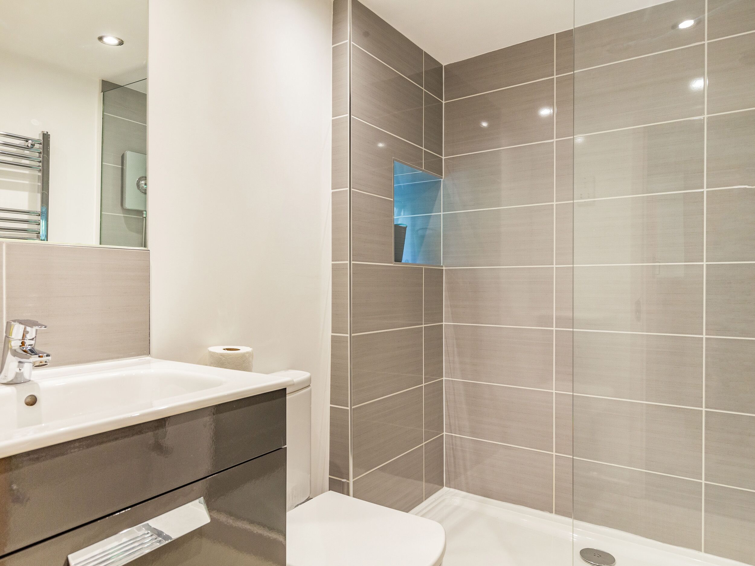 Un baño moderno con un lavamanos blanco, inodoro y zona de ducha.