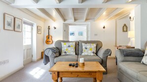 A cozy living room with a wooden coffee table, two grey sofas, and a guitar on the wall. - 3 Rose Cottages (St. Agnes)
