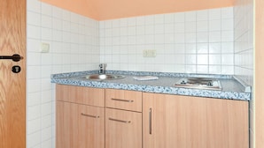 Una piccola cucina con lavello, fornelli e mobili in legno.