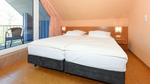 Un letto matrimoniale con una struttura scura, due comodini con lampade, una finestra vista esterna e una sedia vicino alla finestra.