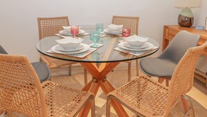 A round glass table with white plates and pink glasses, surrounded by wicker chairs. - East Newk Cottage (Bridlington)