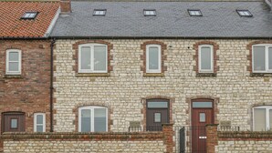 A stone building with multiple windows and doors, featuring a mix of brick and stone construction. - East Newk Cottage (Bridlington)