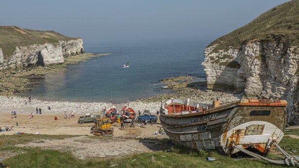 A coastal scene with a boat named 'SPRING FLOWER' docked at a beach with rocky cliffs. - East Newk Cottage (Bridlington)