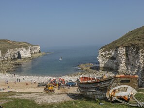 A coastal scene with a boat named 'SPRING FLOWER' docked at a beach with rocky cliffs. - East Newk Cottage (Bridlington)