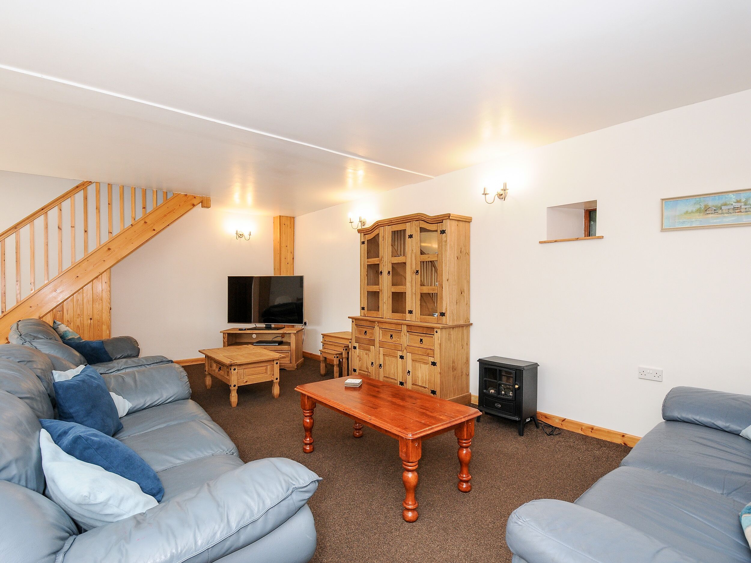 A living room with a wooden staircase, a television, a cabinet, and a sofa.