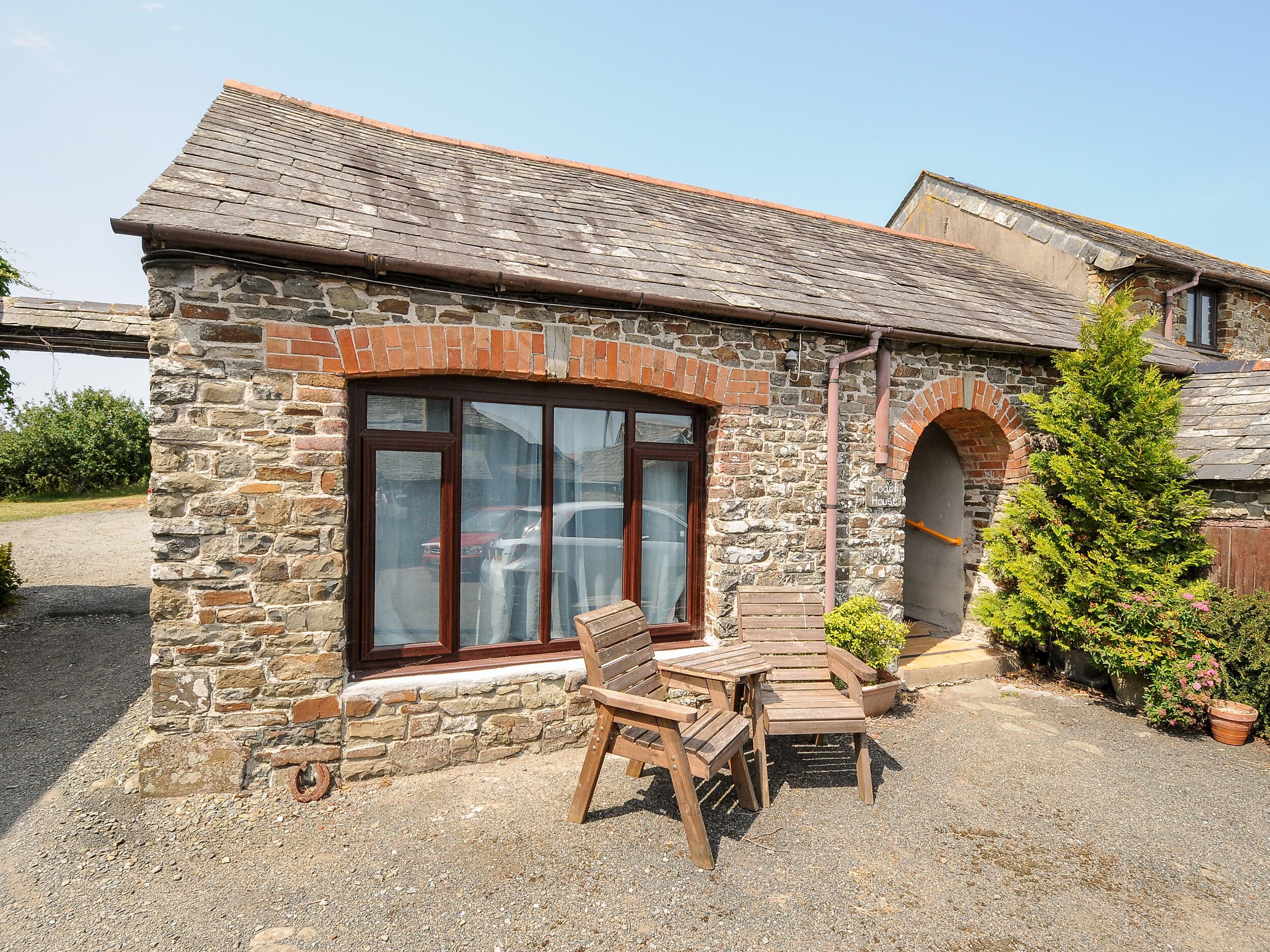 A stone building with a large window, a wooden bench, and a potted plant.
