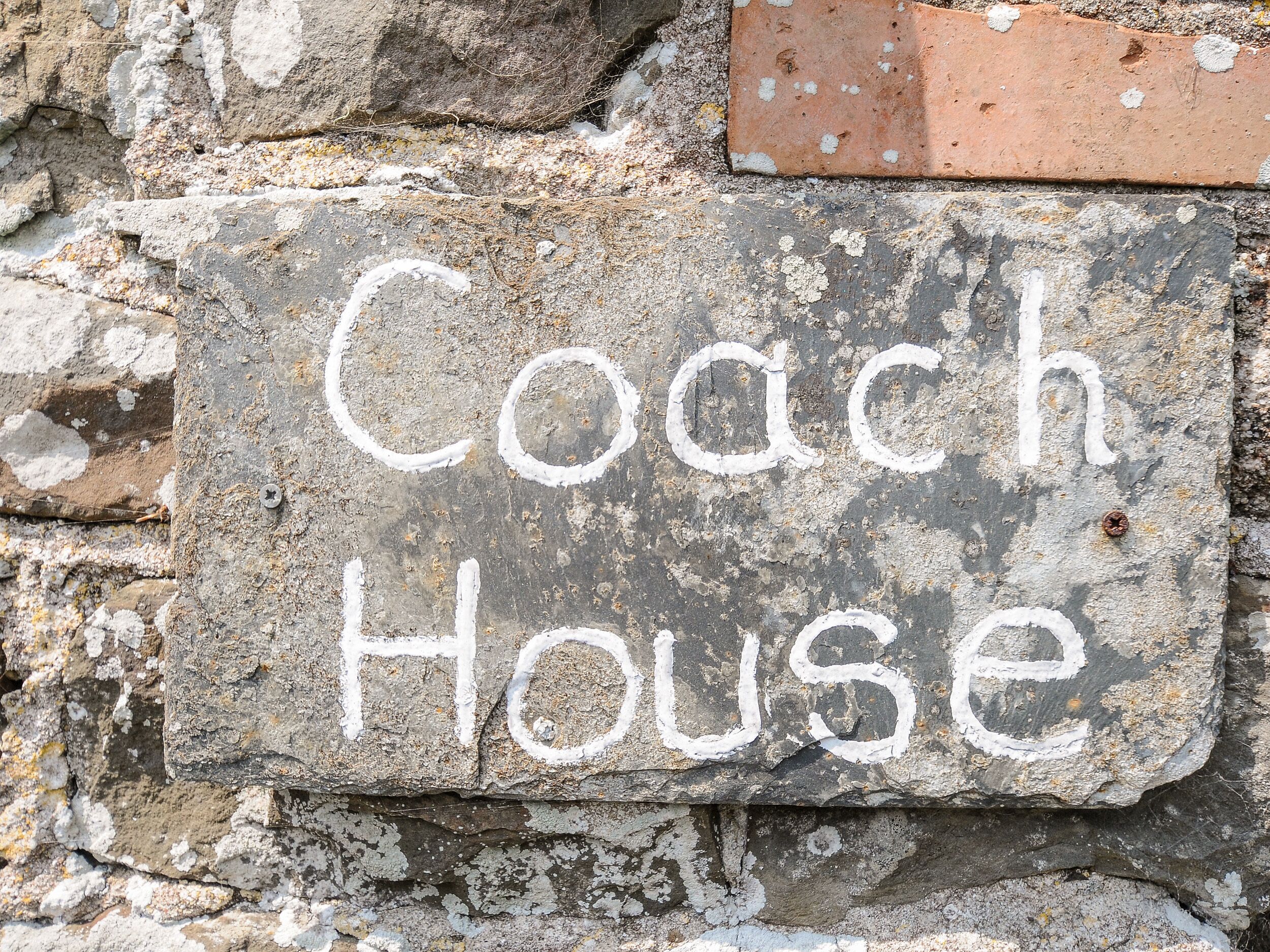 A stone sign with the words "Coach House" painted on it.