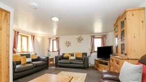 A living room with two leather sofas, a wooden coffee table, and a TV stand. - The Wagon Linney (Bude)