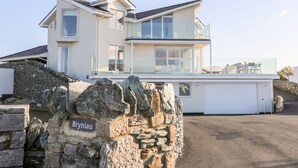 Una moderna casa a due piani con un muro in pietra su cui è riportata la scritta 'Bryniau' in primo piano.