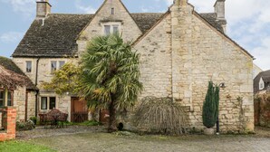A stone building with a cobblestone driveway, a palm tree, and a brick wall with a green topiary. - Chapel House (Stonehouse)