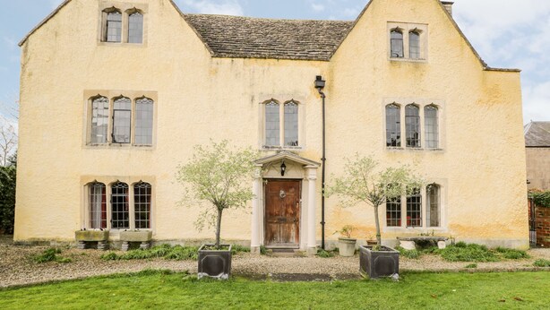 A two-story house with a symmetrical facade, a central entrance with a wooden door, and two potted trees in front. - Chapel House (Stonehouse)
