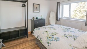 A bedroom with a bed, dresser, and a window with a view of trees. - Isallt (Caernarfon)