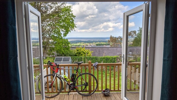 A view from a room with a wooden deck, a bicycle, and a solar panel outside. - Isallt (Caernarfon)