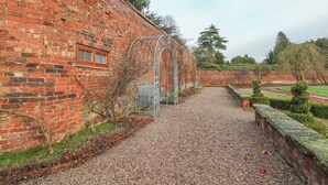 A brick building with a gravel path leading to a bench area. - Lakeside Cottage (Macclesfield)