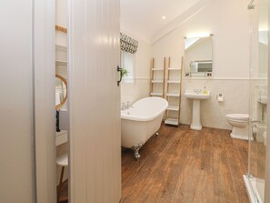 A bathroom with a freestanding bathtub, a pedestal sink, a toilet, and a glass shower enclosure. - Lakeside Cottage (Macclesfield)