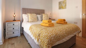 Une chambre bien rangée, avec un lit, deux tables de chevet, une commode et une porte.