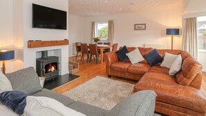 Una sala de estar acogedora con chimenea, sofás de cuero, un comedor y un televisor de pantalla plana.