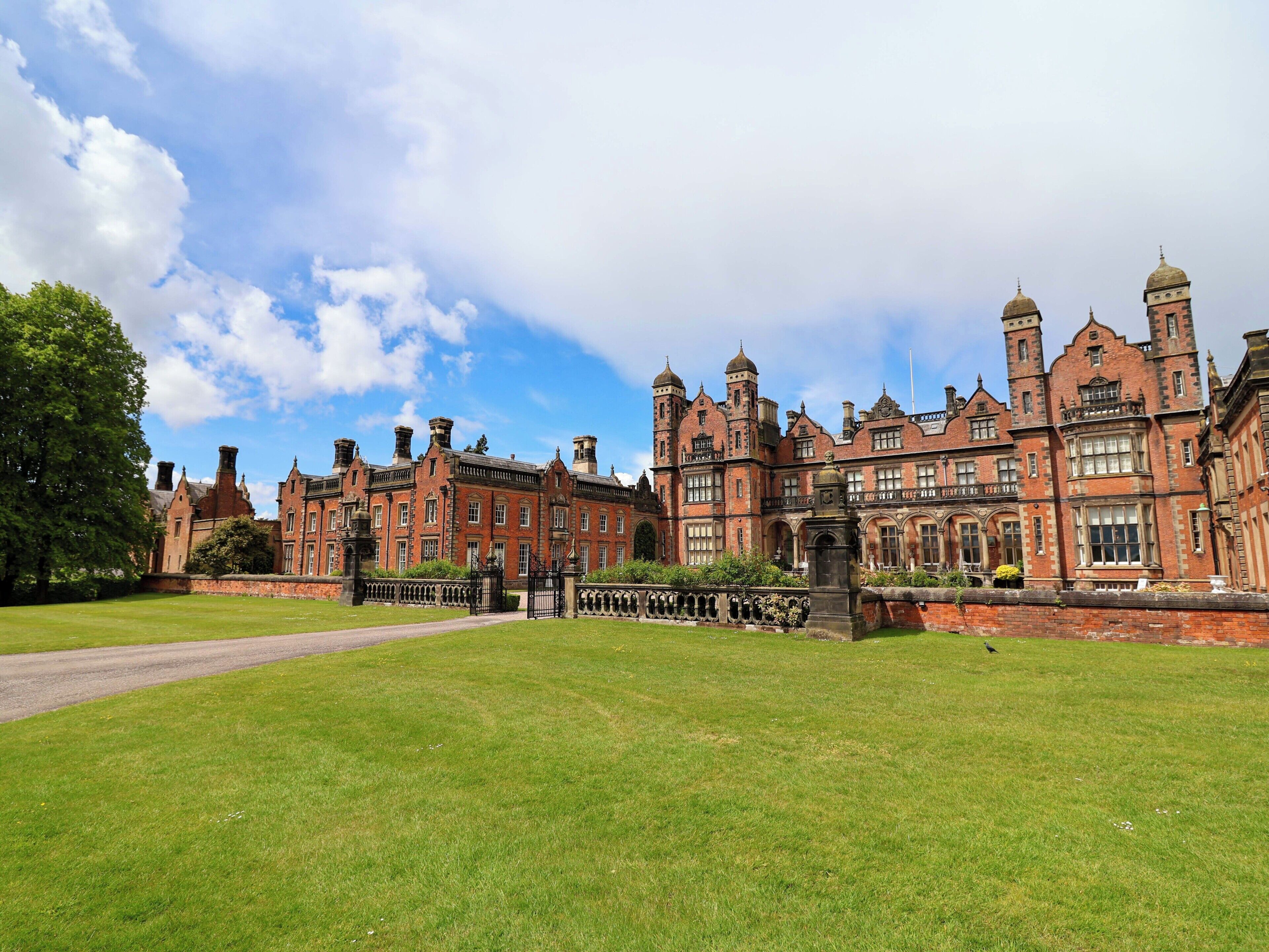 A large, historic building with multiple towers and a well-maintained lawn.