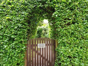 A wooden gate with a sign reading 'SOUTH TOWER' surrounded by dense green foliage. - South Tower Cottage (Macclesfield)