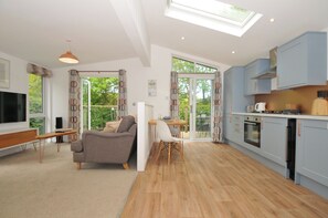 A modern living room with a sofa, TV, and a dining area with a table and chairs.