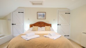 Un dormitorio con una cama grande, dos puertas blancas, un cabecero de madera y un cuadro en la pared.