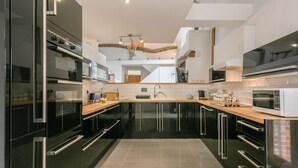 Une cuisine moderne avec des meubles de couleur noire, des appareils en acier inoxydable et un plan de travail en bois.