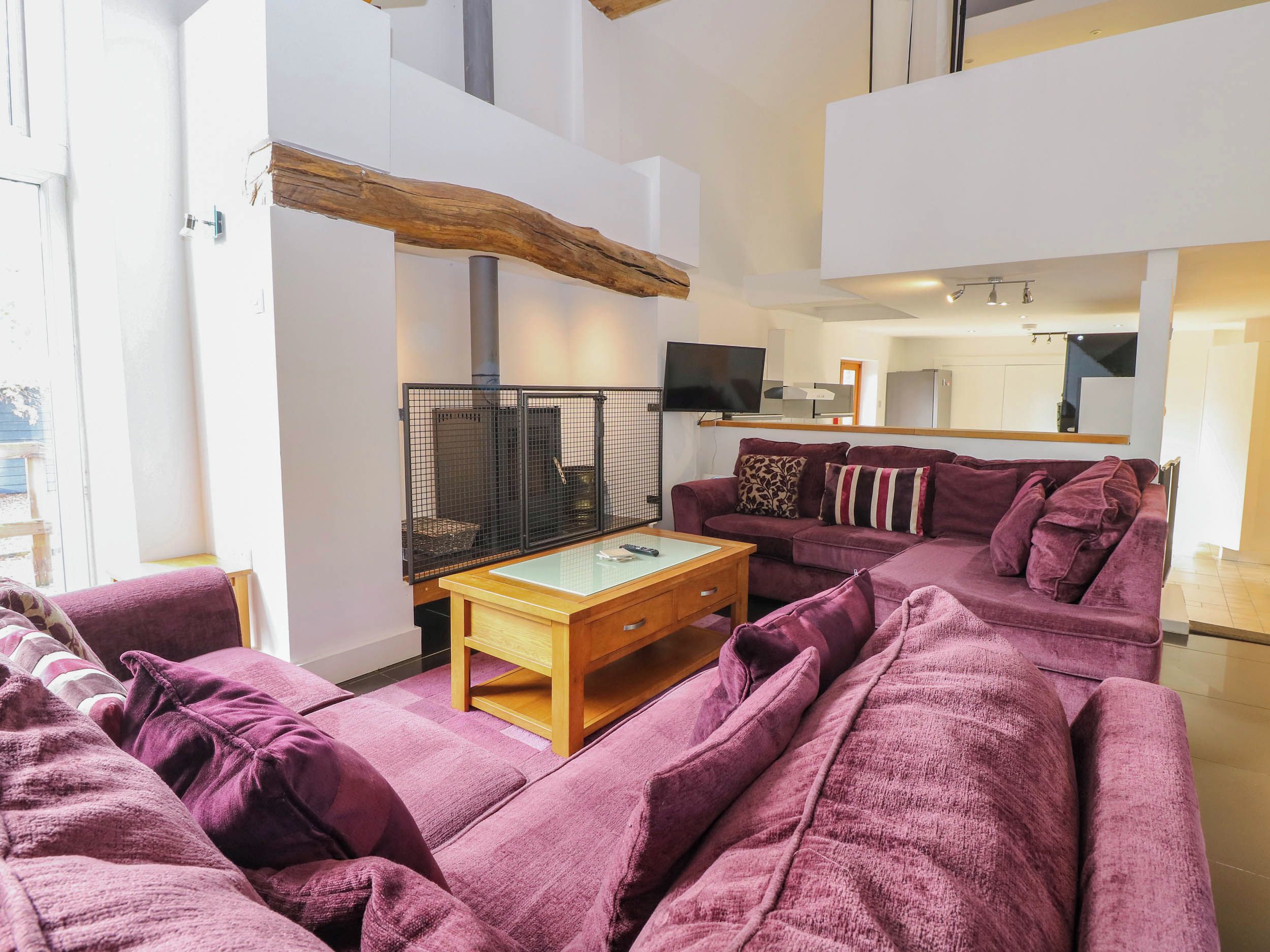 A living room with a purple sofa, a wooden coffee table, and a television.