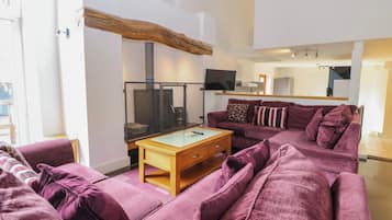 A living room with a purple sofa, a wooden coffee table, and a television.