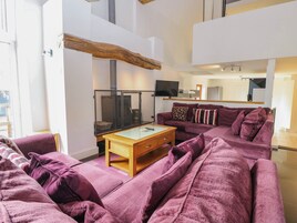 Una sala de estar con un sofá morado, una mesa de centro de madera y una televisión.