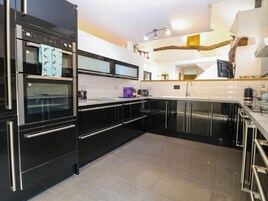 Una cocina moderna con armarios negros, horno empotrado y pileta de acero inoxidable.